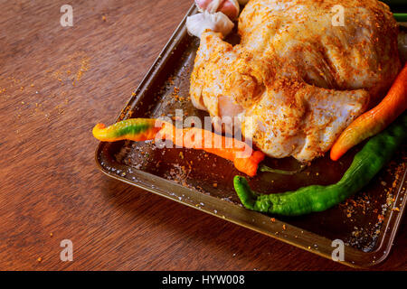 Whole Raw Chicken in iron pan marinated and ready to cook with ingredients for cooking. on stone background. Stock Photo