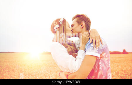 happy young hippie couple kissing in field Stock Photo