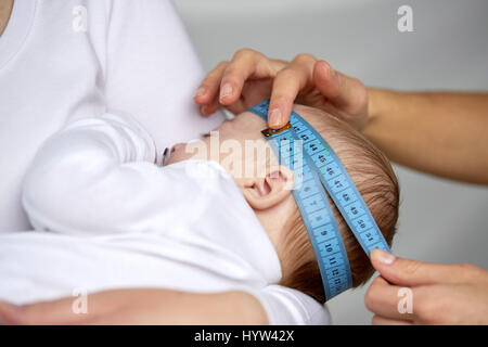 close up of hands with tape measuring baby head Stock Photo