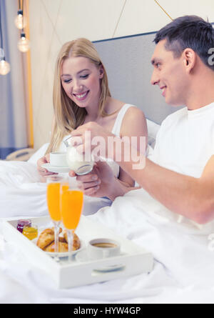 smiling couple having breakfast in bed in hotel Stock Photo