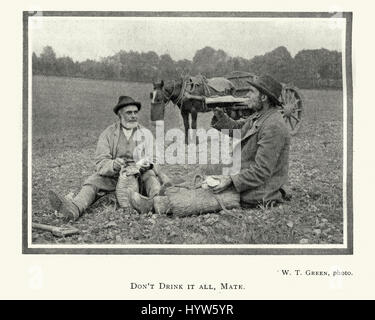 Vintage photograph of Two farmer workers having lunch and drinking in a field, 1913 Stock Photo