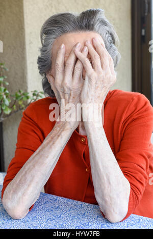 Grunge portrait of an old woman with her hands on her head Stock Photo