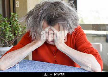 Grunge portrait of an old woman with her hands on her head Stock Photo