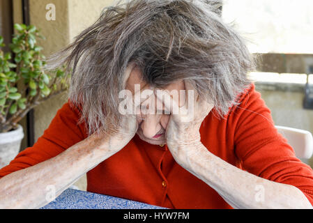 Grunge portrait of an old woman with her hands on her head Stock Photo