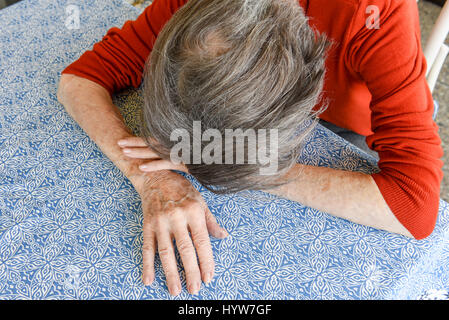 Grunge portrait of an old woman with her hands on her head Stock Photo