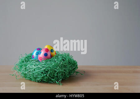 easter eggs in an artificial grass nest on table Stock Photo