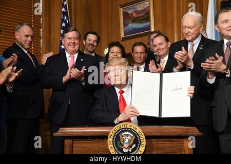 Washington DC, USA. 26th April, 2017. U.S President Donald Trump surrounded by Interior Secretary Ryan Zinke, left, and Congressional Republicans holds up the signed Antiquities Executive Order at the Interior Department April 26, 2017 in Washington, D.C. The order calls into question the future of dozens of national monuments and will allow companies to mine and drill for oil in protected lands. Credit: Planetpix/Alamy Live News Stock Photo