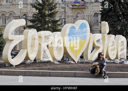 Kiev, Ukraine. 26th Apr, 2017. A woman seats near the logo of the Eurovision Song Contest 2017, at the Independence Square in center of Kiev, Ukraine, on 26 April 2017. The will contest consist of two semi-finals that will be held on 9 and 11 May and a grand final that will take place at the International Exhibition Centre in Kiev on 13 May. Credit: Serg Glovny/ZUMA Wire/Alamy Live News