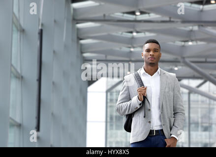 Portrait of a cool young man walking inside station building with bag Stock Photo