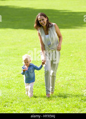 Portrait of a smiling mother and daughter walking on grass Stock Photo
