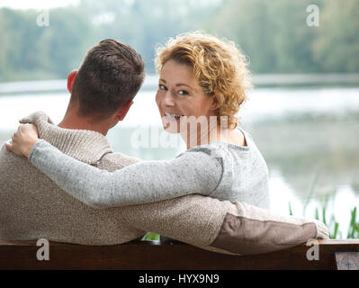 Portrait of a happy couple sitting on bench outdoors Stock Photo