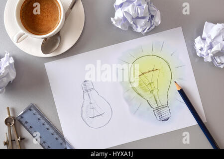 Concept of business idea with representation of the development of a plan with two bulbs drawn on a sheet. With pencil, crumpled sheets, ruler and cof Stock Photo