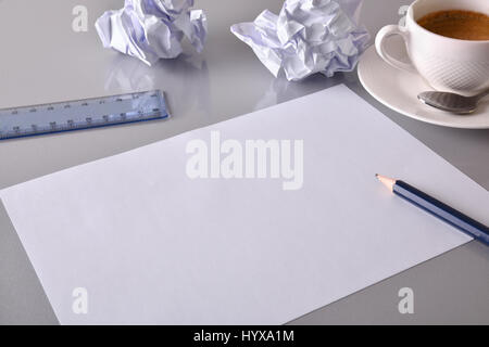 Concept search for ideas in business. Blank sheet on gray office table with crumpled sheets, coffee, rule and compass in the background. Elevated view Stock Photo