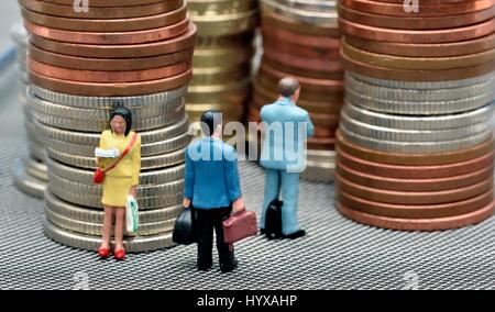 Miniature figurines standing in front of stacks of coins. Stock Photo