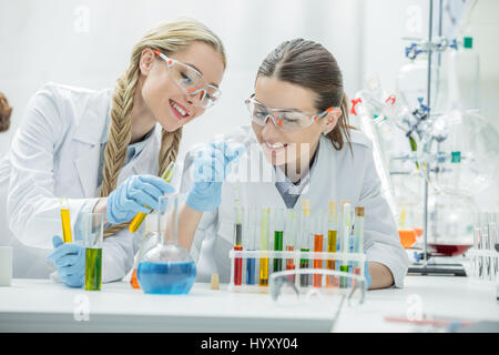 Two young female scientists making experiment in chemical laboratory Stock Photo