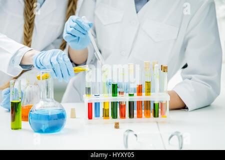 Mid section view of female scientists working with reagents in laboratory Stock Photo