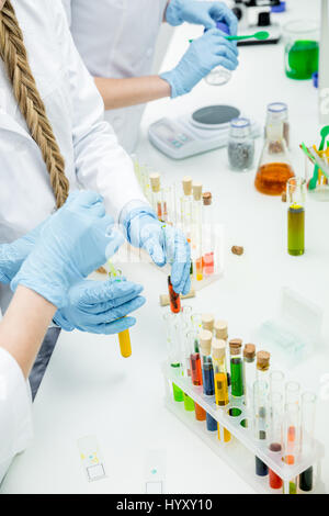 Mid section view of female scientists working with reagents in laboratory Stock Photo