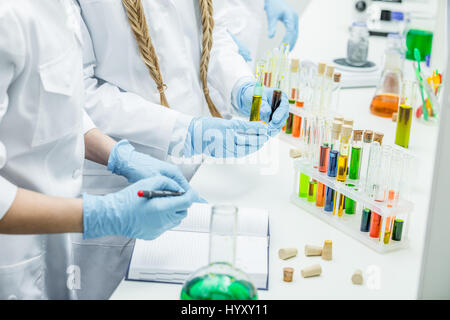 Mid section view of female scientists working with reagents in laboratory Stock Photo