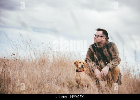 Man and dog resting in grassland Stock Photo