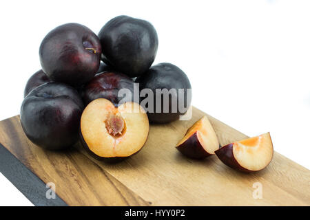 Ripe tasty plums on the wooden board, isolated on white background with clipping path Stock Photo