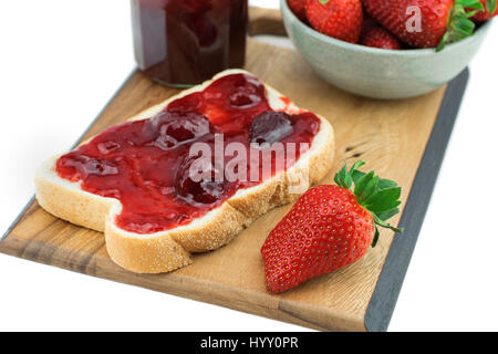 Bread with strawberry jam on a wooden board. Tasty breakfast , Ripe strawberries isolated on white background. Stock Photo