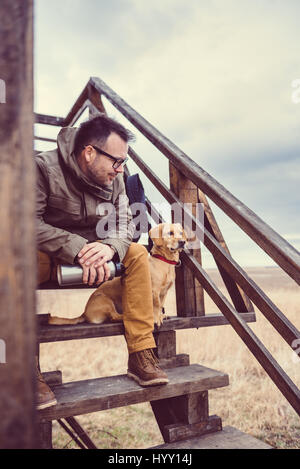 Hiker and dog sitting on the stairs of hikers rest cabin Stock Photo