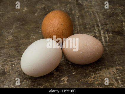 Three fresh chicken eggs on an old wooden table Stock Photo