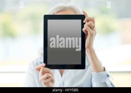 Woman holding digital tablet in front of her face. Stock Photo