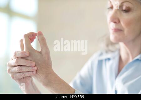 Senior woman holding painful hand. Stock Photo