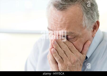 Senior man with hands covering face, close up. Stock Photo