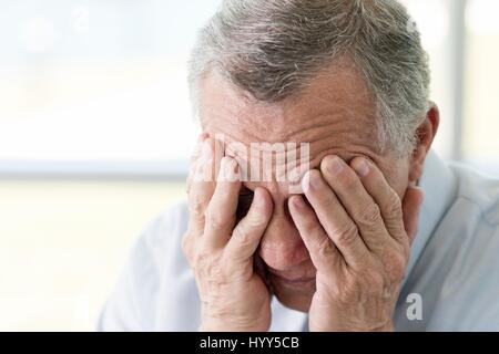 Senior man with hands covering face, close up. Stock Photo