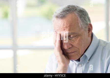 Senior man rubbing face. Stock Photo