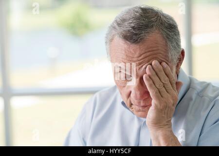 Senior man rubbing face. Stock Photo