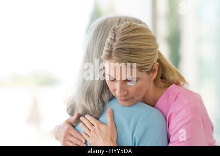 Female care worker embracing female patient. Stock Photo