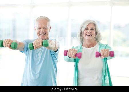 Senior couple using hand weights, laughing. Stock Photo