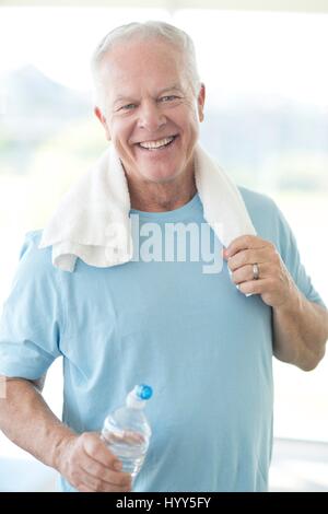 Senior man in gym with water bottle and towel. Stock Photo