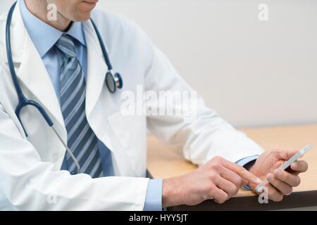 Male doctor using smartphone. Stock Photo