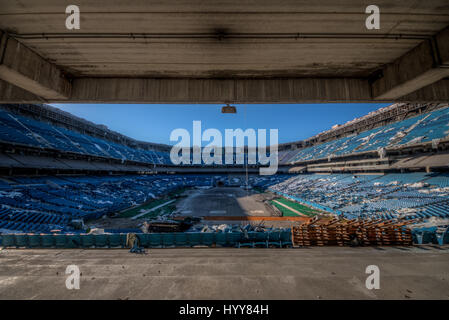 PONTIAC, USA: HAUNTING pictures have revealed the crumbling remains of an 82,000 seat American football stadium that saw its last touchdown long ago. The eerie images show the rows of thousands of blue plastic seats which now lie empty in view of the scorched square of earth where the lush green pitch once was. Other shots of the former Detroit Lions stadium show rubble-strewn remnants of the VIP boxes and forgotten beer bottles and condiments left sitting on a table. The creepy snaps were taken at the Pontiac Silverdome in Pontiac, Michigan by American photographer Jeff Hagerman (36) from Atl Stock Photo