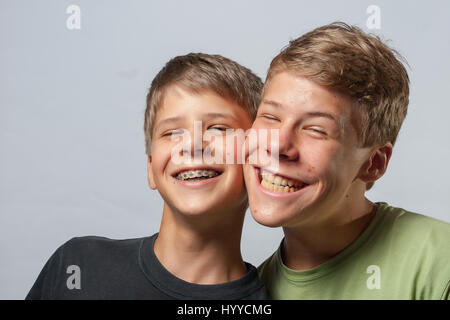 Two boys, cheeks touching making funny faces Stock Photo
