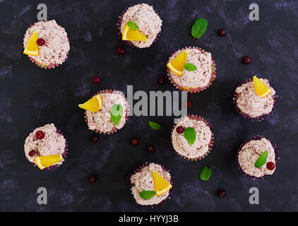 Lemon cupcakes with cherry cream. Cranberry, mint leaves. Food on a dark background. Top view Stock Photo