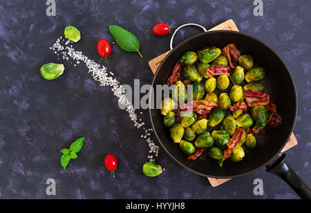Roasted brussels sprouts with bacon on dark background. Top view Stock Photo