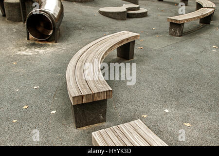 Empty curved wooden benches on a kids playgrond. Stock Photo