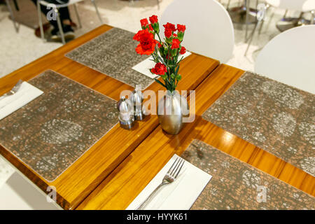 Tables are set and decorated with carnations at a restaurant in an airport. Stock Photo