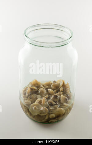 in a glass jar small amount of mushrooms in marinade Stock Photo