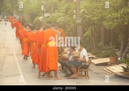 Luang Prabang, Laos - 20 June, 2014: Buddhist monks collecting alms from people on the street of Luang Prabang, Laos on 20 June, 2014. Stock Photo