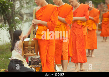 Luang Prabang, Laos - 20 June, 2014: Buddhist monks collecting alms from people on the street of Luang Prabang, Laos on 20 June, 2014. Stock Photo