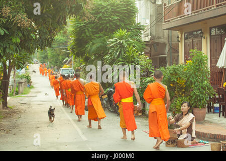 Luang Prabang, Laos - 20 June, 2014: Buddhist monks collecting alms from people on the street of Luang Prabang, Laos on 20 June, 2014. Stock Photo