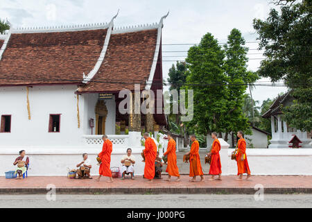 Luang Prabang, Laos - 22 June, 2014: Buddhist monks collecting alms from people on the street of Luang Prabang, Laos on 22 June, 2014. Stock Photo