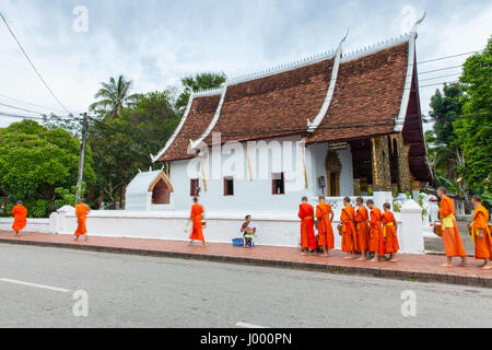 Luang Prabang, Laos - 22 June, 2014: Buddhist monks collecting alms from people on the street of Luang Prabang, Laos on 22 June, 2014. Stock Photo