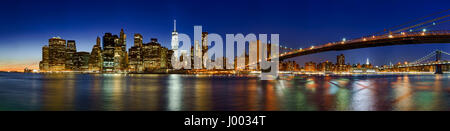 Panoramic view of Lower Manhattan Financial District skyscrapers at twilight with the Brooklyn Bridge. New York City Stock Photo